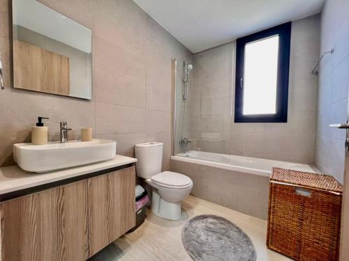 a bathroom with a sink and a toilet and a tub at Mackenzie Seaside Apartment in Larnaka