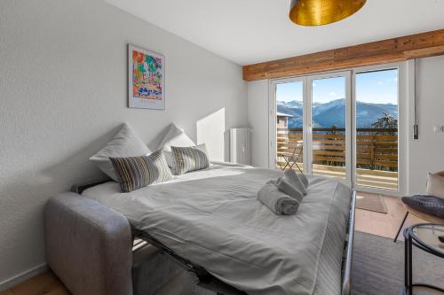 a bed in a room with a large window at Appartement fraîchement rénové à Crans-Montana, vue imprenable in Crans-Montana
