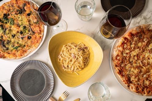 a table with plates of pasta and glasses of wine at Catalonia Barcelona Beach in Barcelona