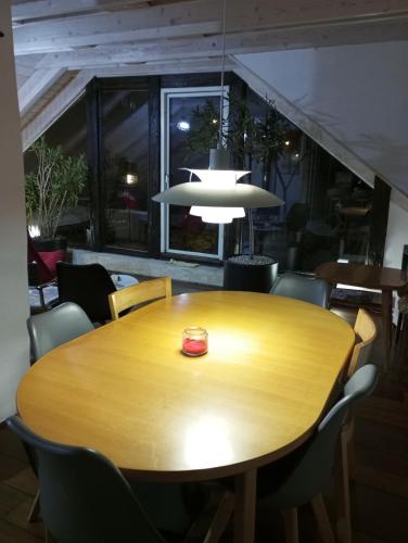 a wooden table in a room with chairs and aendant light at Nové podkrovie umelca in Trnava