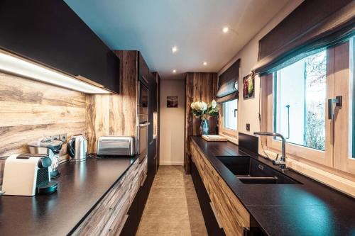 - une cuisine avec des comptoirs noirs et un évier dans l'établissement Appartement au coeur du village de Megève, à Megève