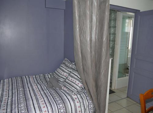 - une chambre avec un lit et un rideau au-dessus dans l'établissement la maison jaune proche mer et marché avec wifi, à Pornichet