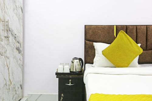 a bed with a yellow pillow and candles on a nightstand at Twamev Residency in New Delhi