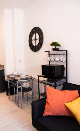 a living room with a table and a clock on the wall at Amazing Apartment in Warrington in Warrington