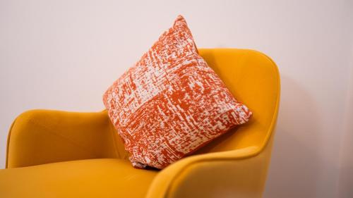 a red pillow sitting on an orange chair at Amazing Apartment in Warrington in Warrington