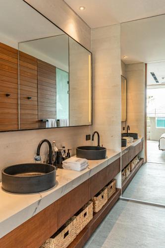 two sinks in a bathroom with two mirrors at Body Factory Lifestyle Residence in Canggu