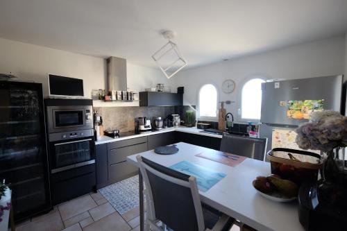 Il comprend une cuisine avec une table et des appareils électroménagers. dans l'établissement 125M2 FACE MER ST BRéVIN, à Saint-Brévin-les-Pins