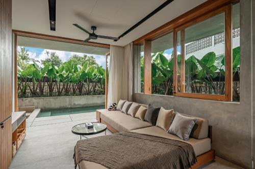 a living room with a couch and a large window at Body Factory Lifestyle Residence in Canggu