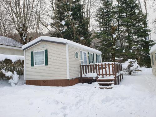 une maison recouverte de neige avec un banc devant elle dans l'établissement Mobile-home confort 3 chambres au camping, La Bourboule, à La Bourboule
