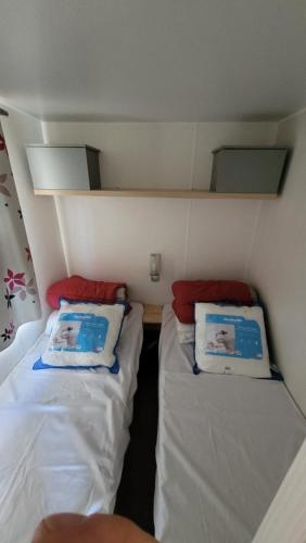 une petite chambre avec deux lits dans un bateau dans l'établissement Mobile-home confort 3 chambres au camping, La Bourboule, à La Bourboule