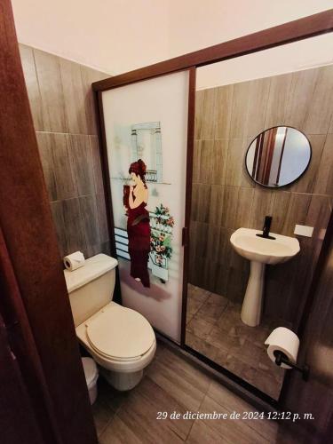 a bathroom with a toilet and a picture of a woman at Hotel Colonos Los Cabos in Cabo San Lucas