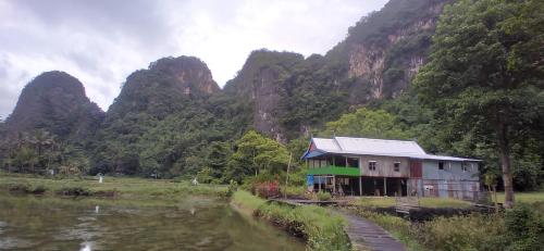 a house on the side of a river next to a mountain at Berua homestay Rammang Rammang in Maros