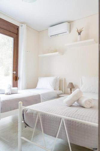 a white bedroom with two beds and a window at Terra Blue Suites - Nefeli in Kalyves