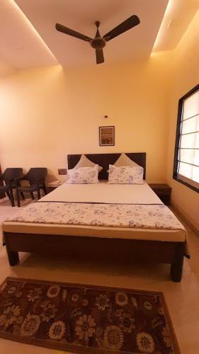 a bedroom with a large bed with a ceiling fan at Windchime Cottages in Alibaug