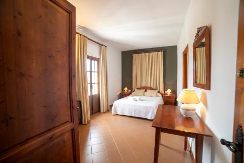 a bedroom with a bed and a table and a window at Villa Turística de Priego in Priego de Córdoba