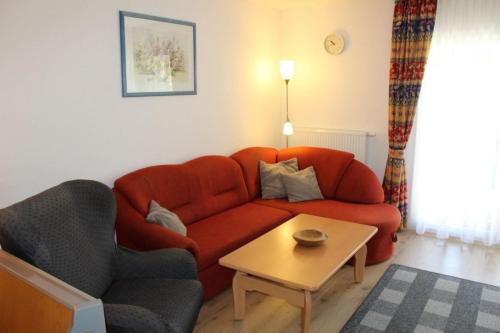 a living room with a red couch and a table at Ferienhaus Nr 48, Kategorie Komfort, Feriendorf Hochbergle, Allgäu in Lechbruck