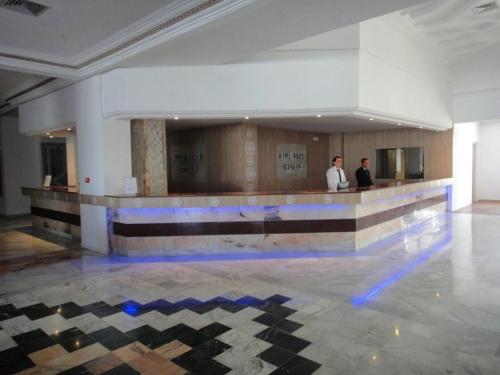 two men standing at a bar in a large room at Aylimas Beach & Resort Monastir in Monastir