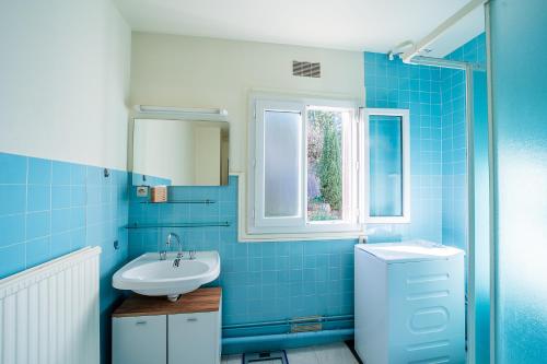 La salle de bains est pourvue de carrelage bleu, d'un lavabo et d'une fenêtre. dans l'établissement Le Vieux Pont - Vue montagne parking privé, à Amélie-les-Bains-Palalda