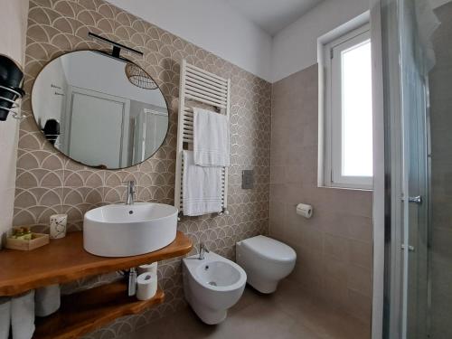 a bathroom with a sink and a toilet and a mirror at Le Dune Luxury Rooms in Vieste