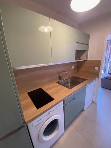 une cuisine avec une machine à laver et un évier dans l'établissement Beau T2 150 m de la plage à Bormes les mimosas, à Bormes-les-Mimosas