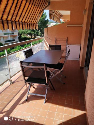 une table et des chaises sur le balcon d'une maison dans l'établissement Beau T2 150 m de la plage à Bormes les mimosas, à Bormes-les-Mimosas