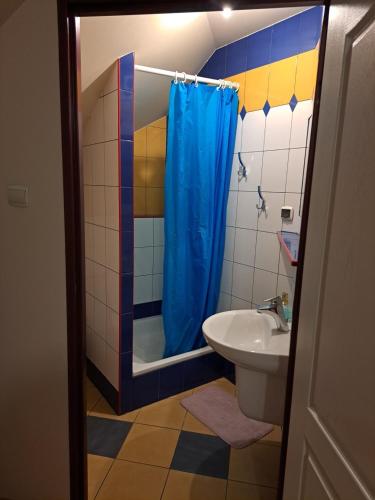 a bathroom with a blue shower curtain and a sink at Agroturystyka Biełka in Giełczyn