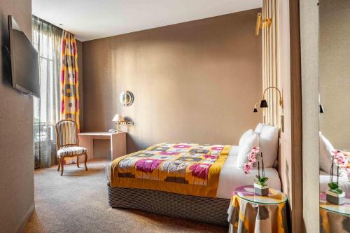 a bedroom with a bed and a table and a chair at Hôtel Regent's Garden - Astotel in Paris
