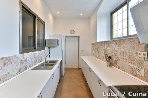 a kitchen with white counters and a sink at MAS DE BERNIS - Masia in L'Aldea