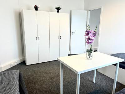 a room with white cabinets and a table with flowers on it at Apart Residence KK in Glinde