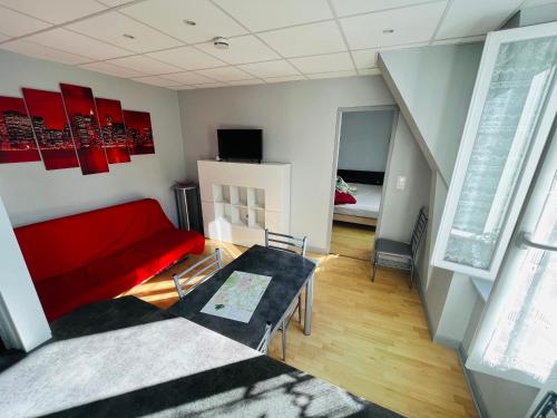 un salon avec un canapé rouge et une table dans l'établissement F2 Pensée, à La Bourboule