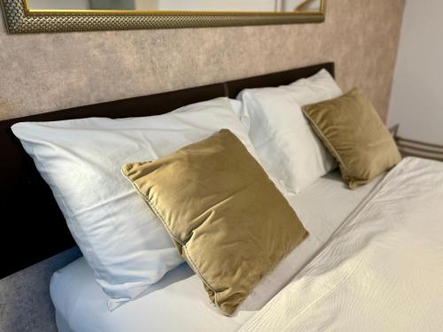 a bed with white pillows and a gold pillow at THE PANAMERICANA, Air-Conditioned, 4K HD TV, Bose, Lounge in Riedstadt