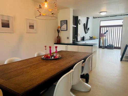 a kitchen with a wooden table and white chairs at Pass the Keys Royal Sands - A Beachside Haven in Camber