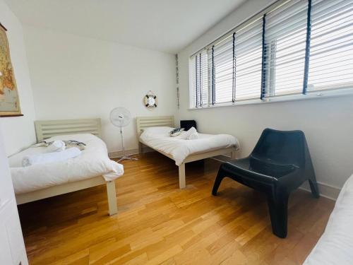 a room with two beds and a chair in it at Pass the Keys Royal Sands - A Beachside Haven in Camber