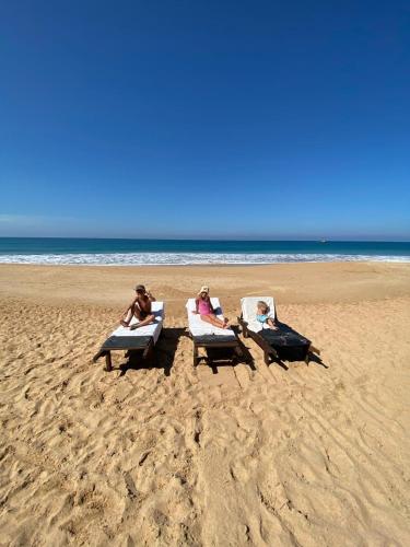 three people sitting in lounge chairs on the beach at Coastal Heaven in Bentota