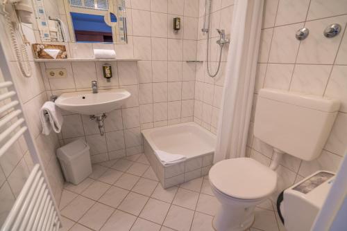 a white bathroom with a toilet and a sink at Airporthotel Residenz Steinenbronn in Steinenbronn