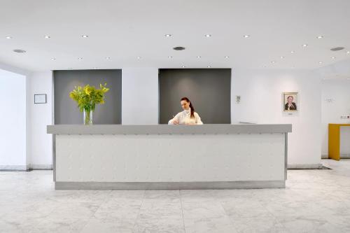 a woman standing behind a counter in a room at Airotel Galaxy in Kavala