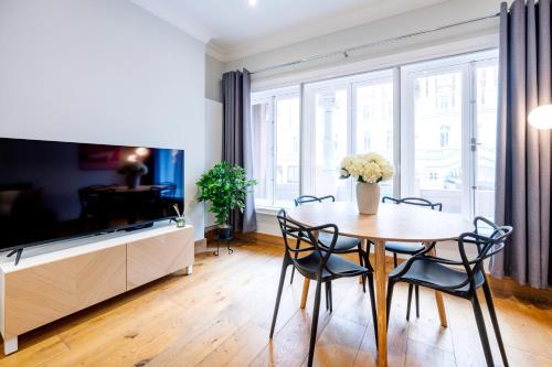 a dining room with a table and chairs and a tv at Welcome London Savoy Strand in London