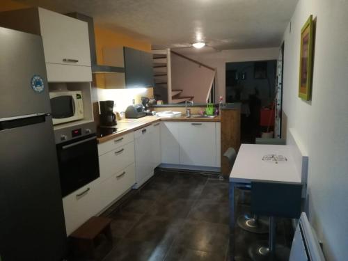 une petite cuisine avec des armoires blanches et un évier dans l'établissement Agréable maison de vacances, à Port-la-Nouvelle