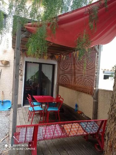 d'un patio avec une table rouge et des chaises sur une terrasse. dans l'établissement Agréable maison de vacances, à Port-la-Nouvelle