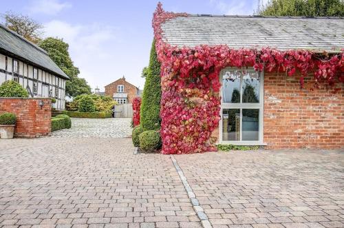 a brick building with a bunch of flowers on it at Stylish Stay Near To Carden Park By Cheshire Escapes in Malpas