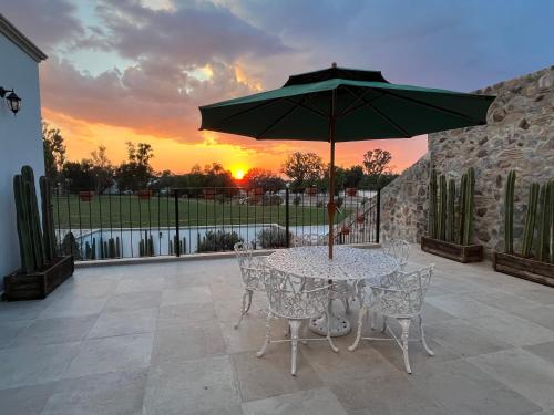 a table and chairs with an umbrella on a patio at Casa Frida con Piscina Privada Caliente, Aire Acondicionado, Billar, Parrilla & FirePit in San Miguel de Allende