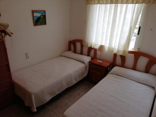 two beds in a small room with a window at Bitacora I Solo Familias Serviplaya!!! in Playa de Xeraco