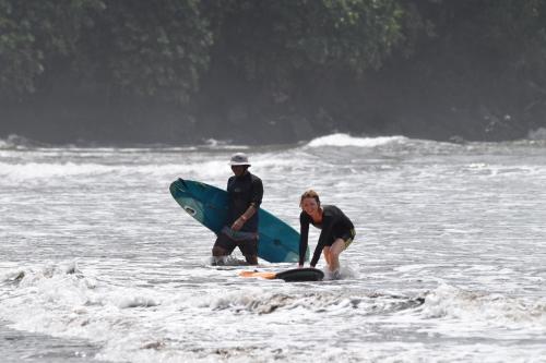 a man and a woman in the water with a surfboard at Air Manis Secret Surfcamp in Taluk Batung
