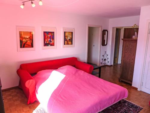 a red bed in a room with a red couch at Apartment Armorial Est Apt- 72 by Interhome in Vermala