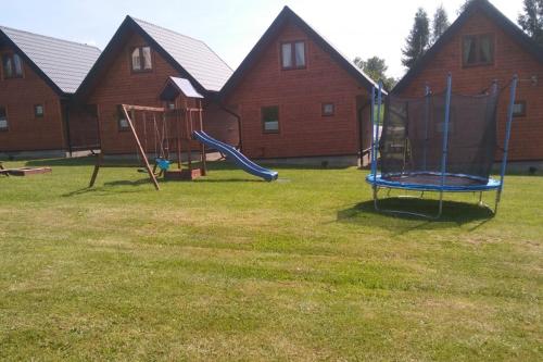 a playground with two swings and a slide in a yard at Domki z sauną Bieszczady Boso po Rosie in Polańczyk
