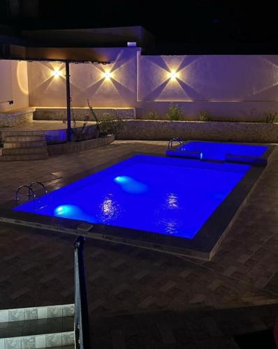 a large blue swimming pool in a backyard at night at Wadi Bani Khalid Villa in Dawwah