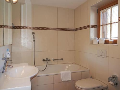 a bathroom with a tub and a sink and a toilet at Apartment Chalet Pfingstrose by Interhome in Grindelwald
