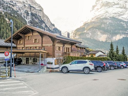 a building with cars parked in front of a mountain at Apartment Chalet Pfingstrose by Interhome in Grindelwald