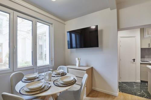 une salle à manger avec une table et des chaises et une télévision dans l'établissement Cozy apartment Montmartre Moulin rouge, à Paris