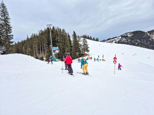 Eine Gruppe von Menschen fährt einen schneebedeckten Hang hinunter. in der Unterkunft Holiday Home Tiny Haus Glockenalm-Schliersee Lodge by Interhome in Aurach